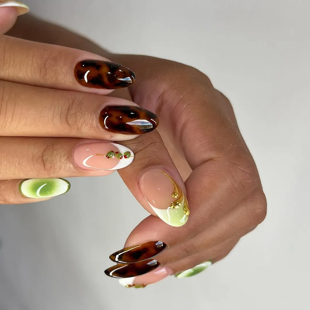 Closeup of a person displaying nail designs featuring marbled and glossy embellishments
