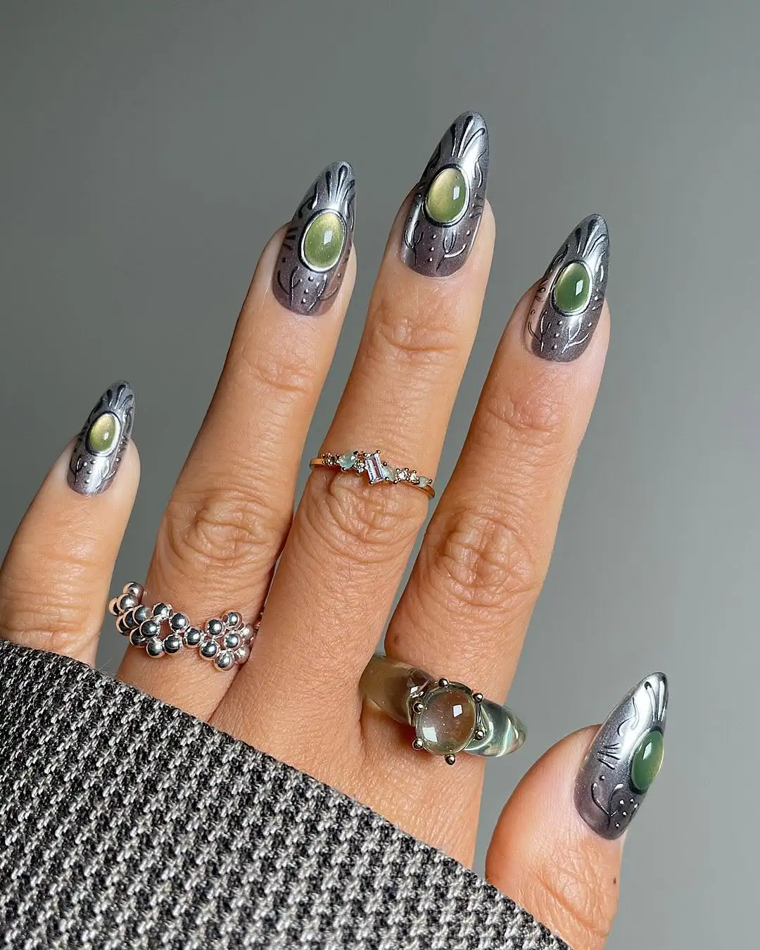 Silver nails with green orbs in the center of each