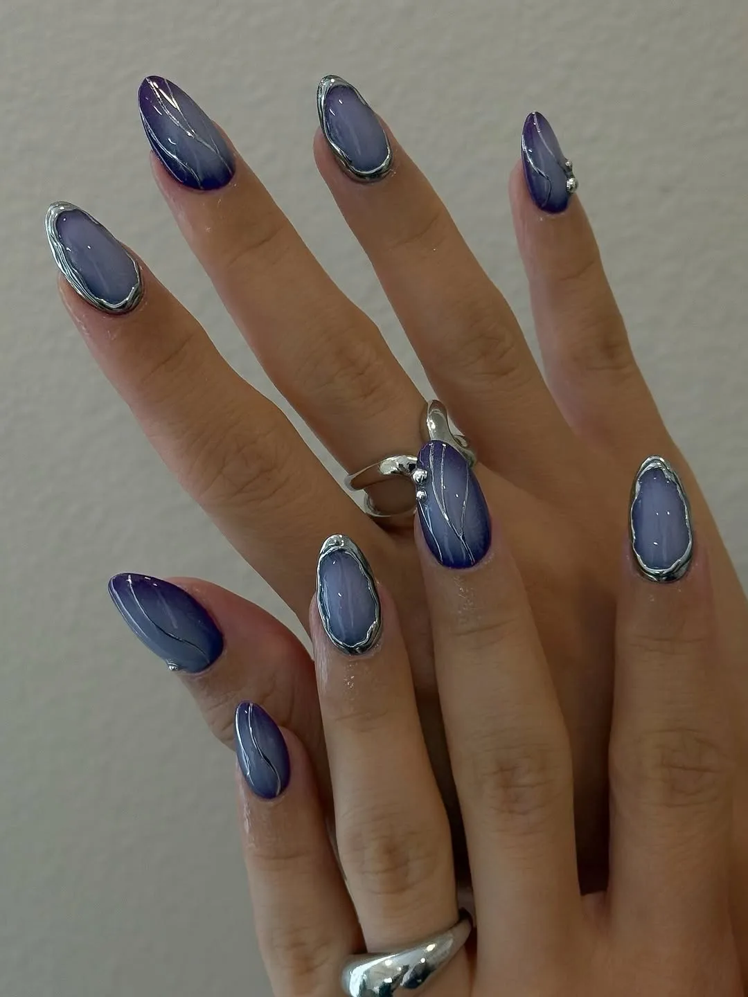 Manicure featuring a navy blue and lavender aura design with silver chrome accents
