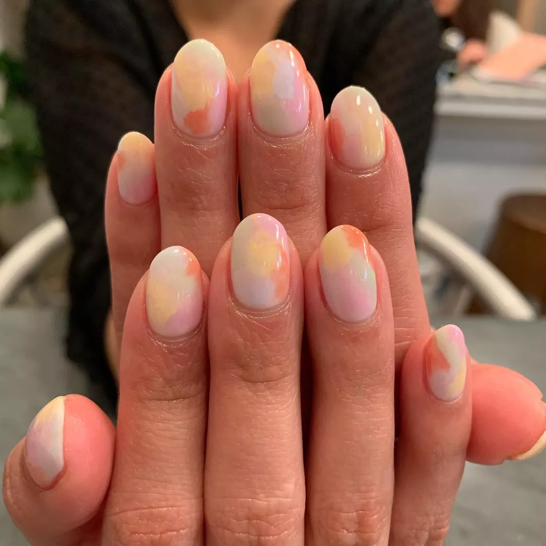Person showing off their oval-shaped nails, which are painted to resemble cotton candy