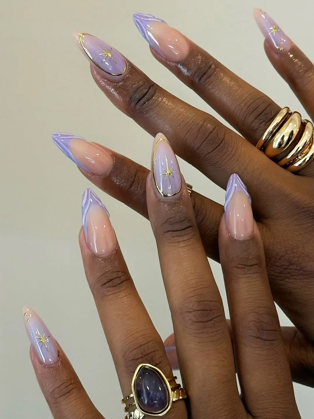 Manicured hands with long pointed nails and delicate rings showcasing intricate nail art designs