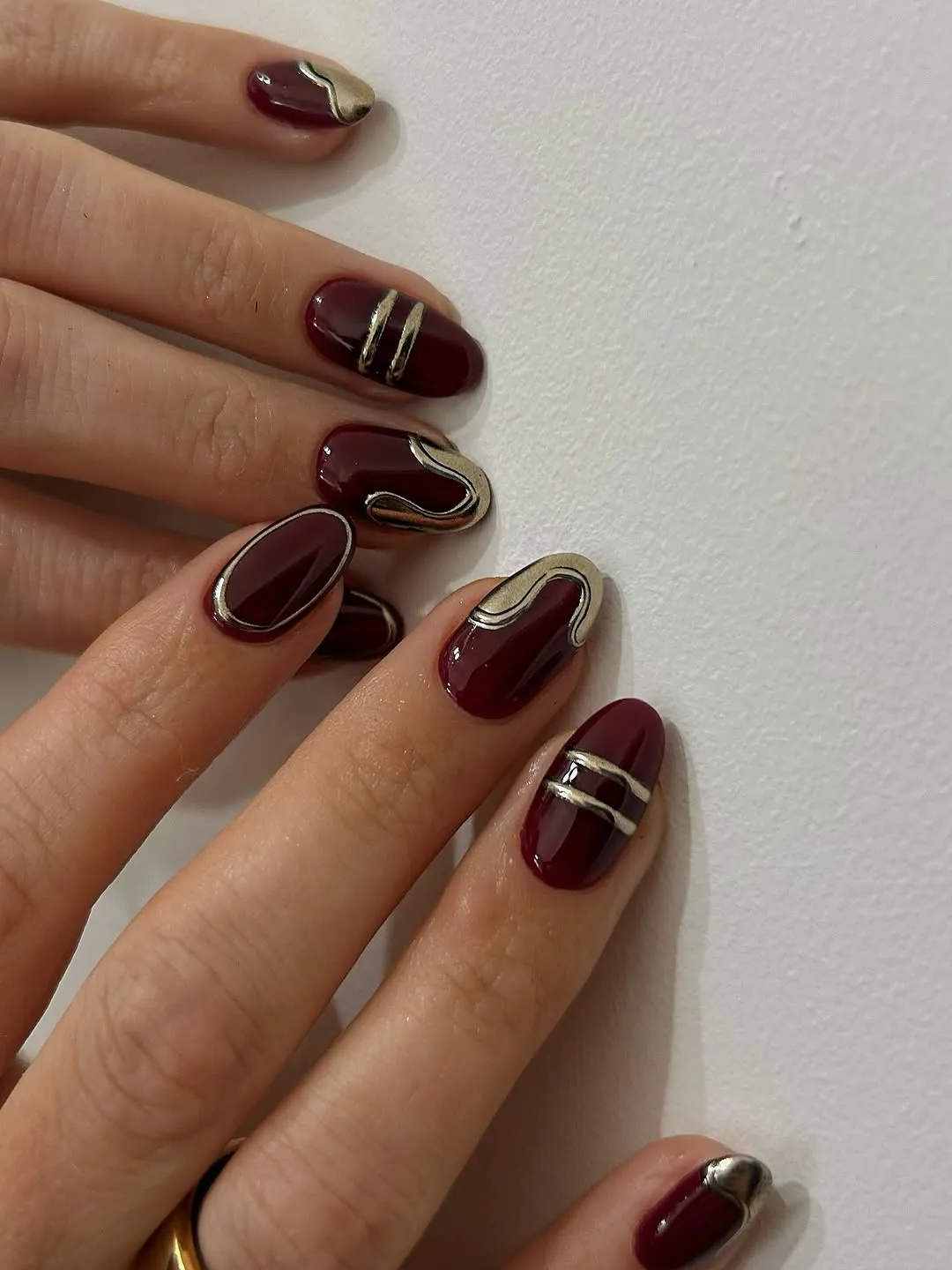 Hands with manicured nails featuring intricate designs and metallic accents