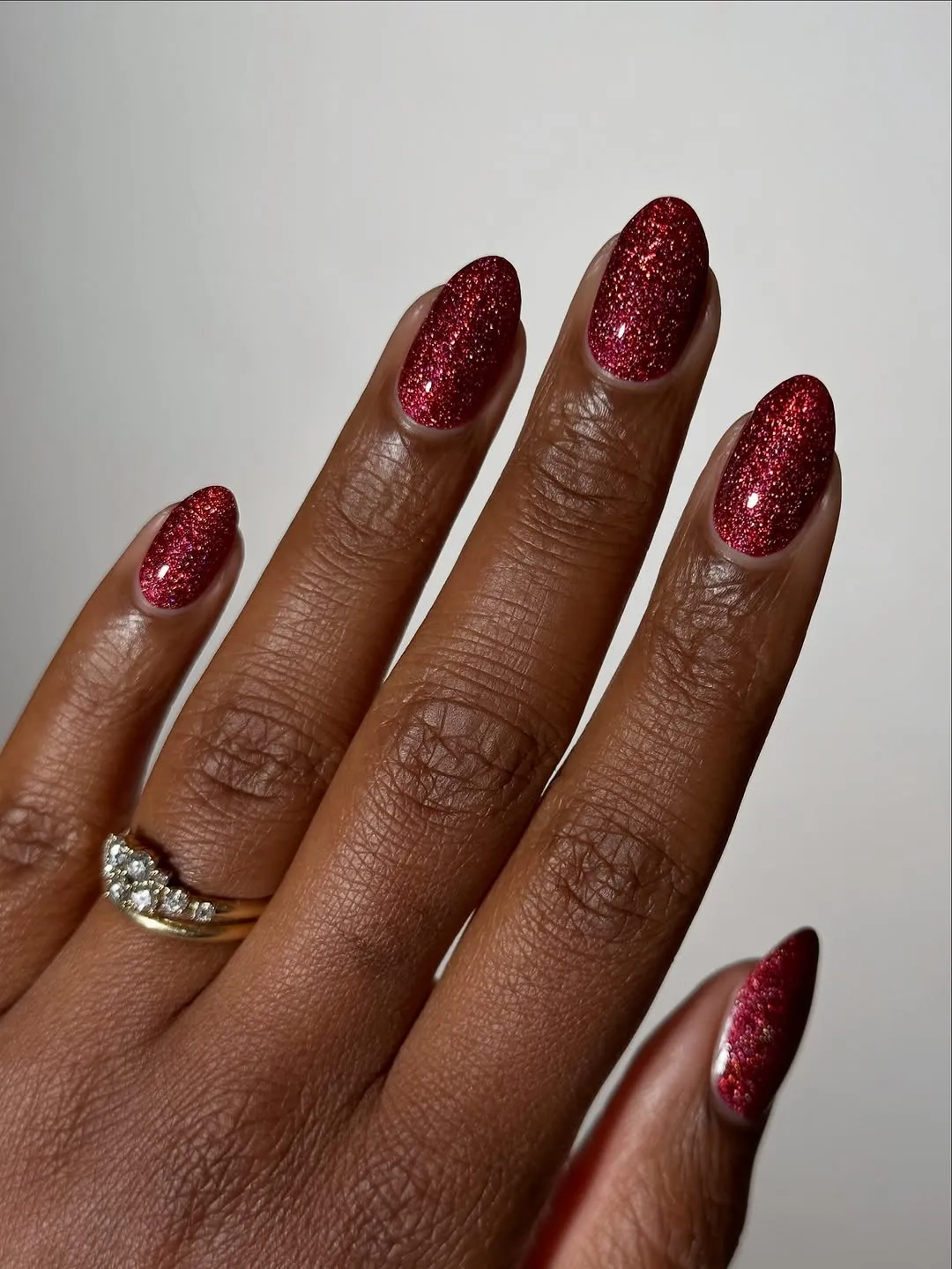 Short nails painted withd ark red glittery polish