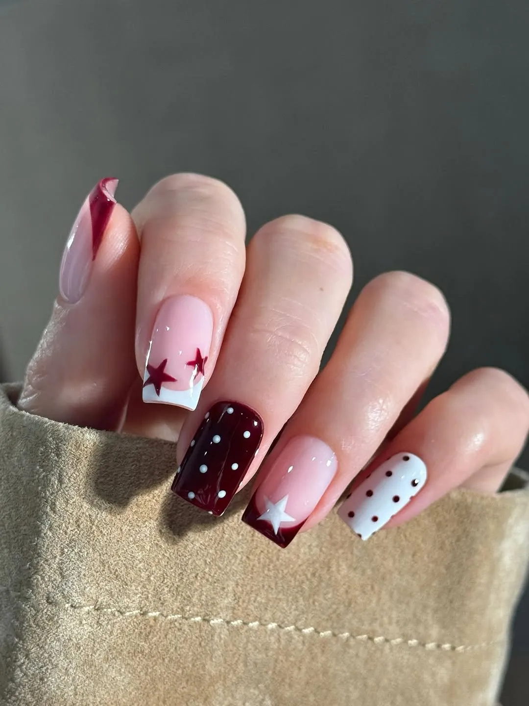 A hand showcasing detailed nail art with star and dot patterns