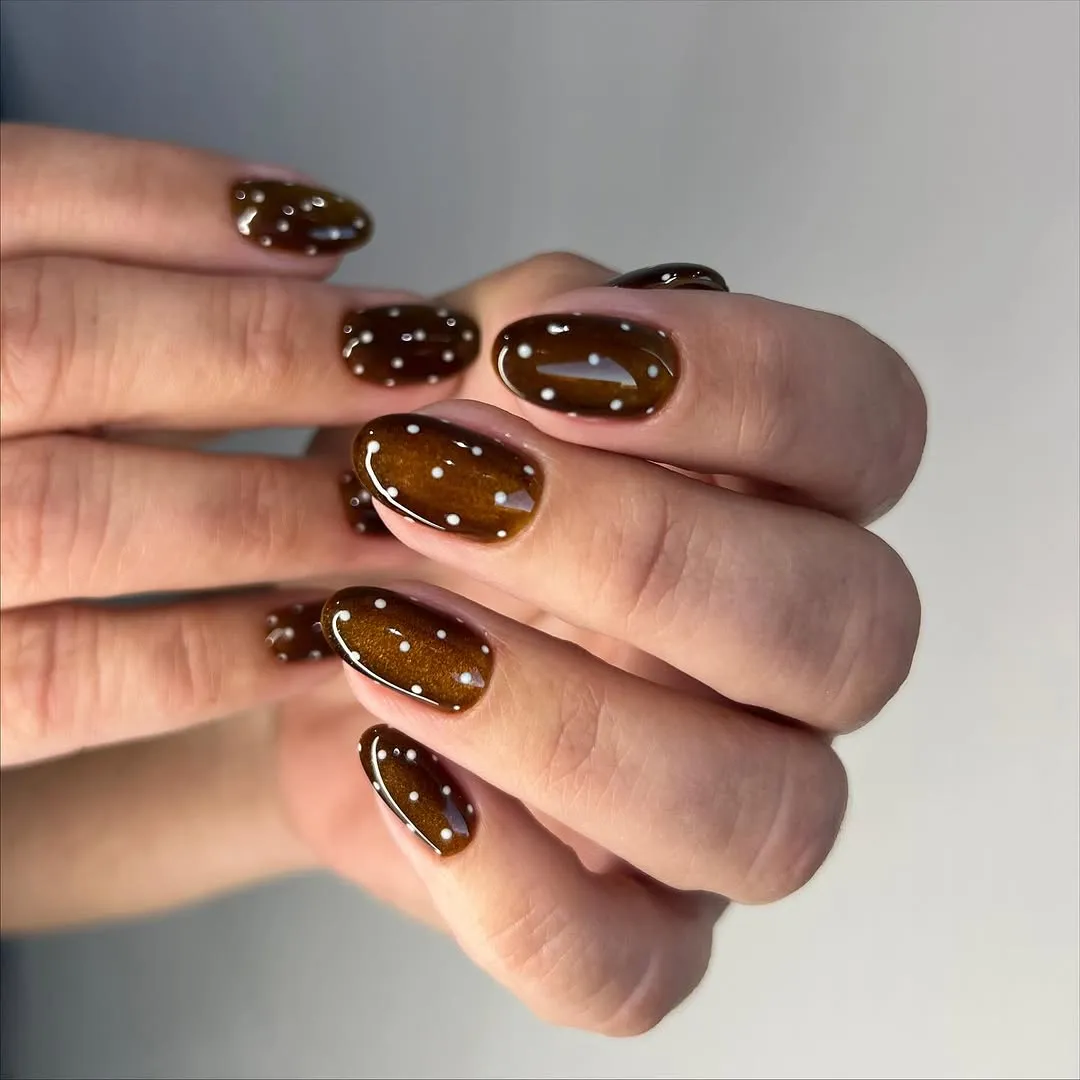Brown cat-eye nails with white polka dots