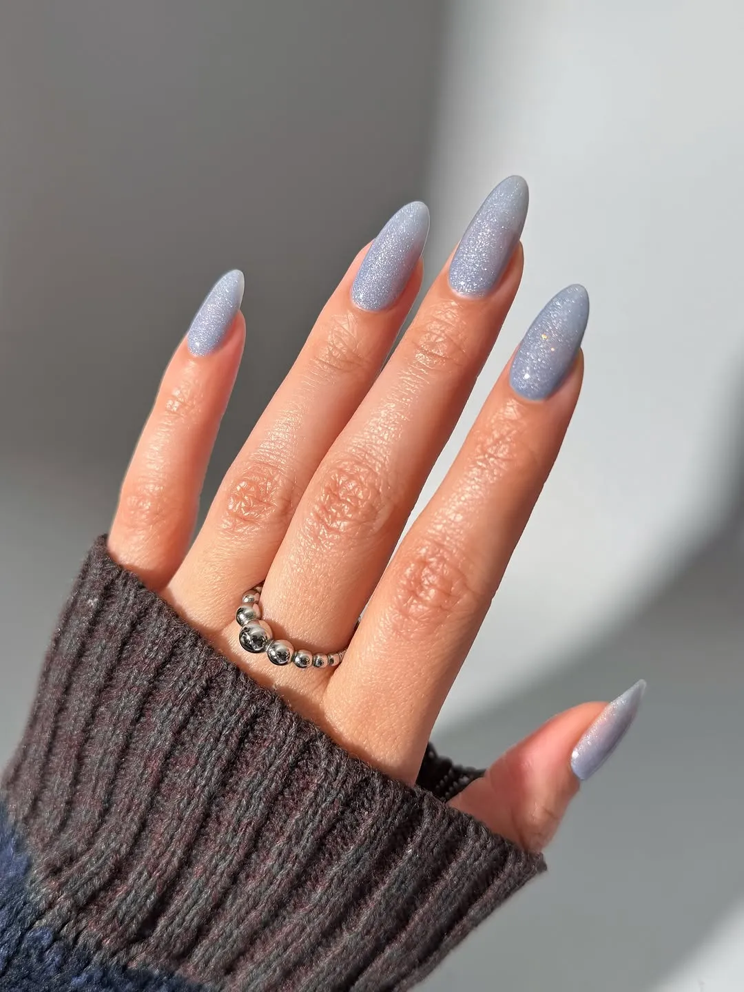 Long almond-shaped nails painted a sparkly light blue