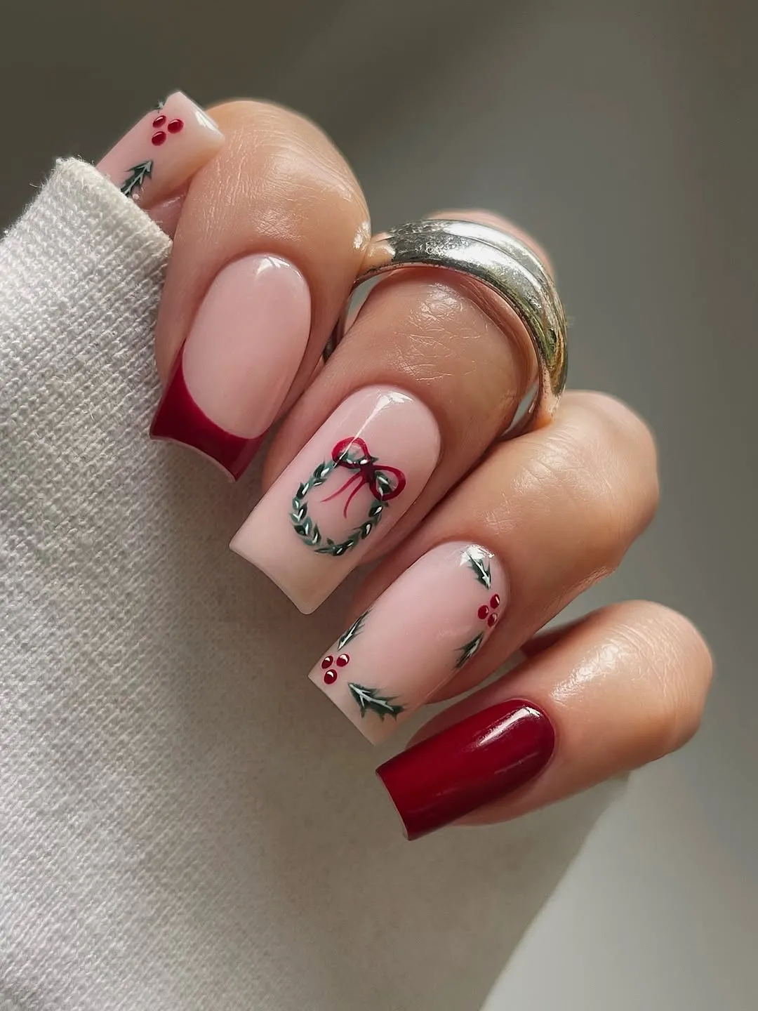 pale pink manicure with red accents and holly decals