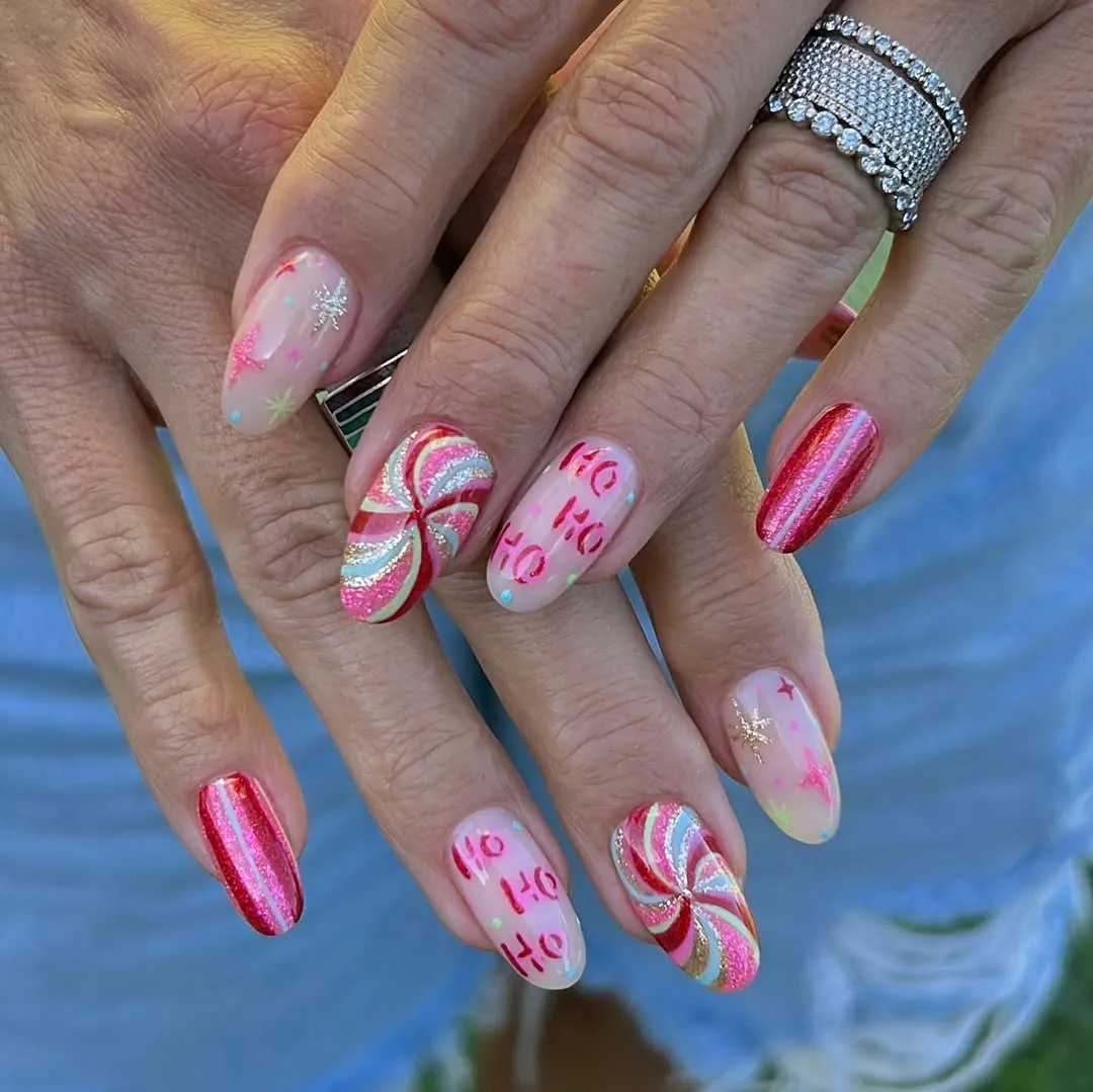 Persons hands showing festive manicured nails featuring Christmasthemed designs and patterns wearing stacked silver rings on one hand
