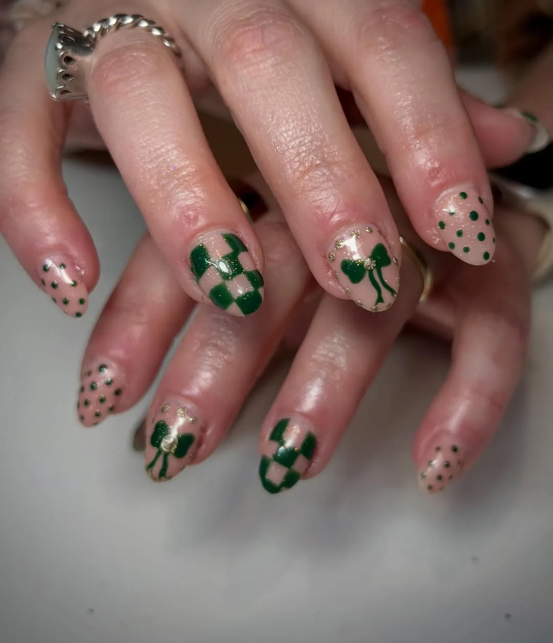 Nails with green polka dots, bows, and checkerboard accents