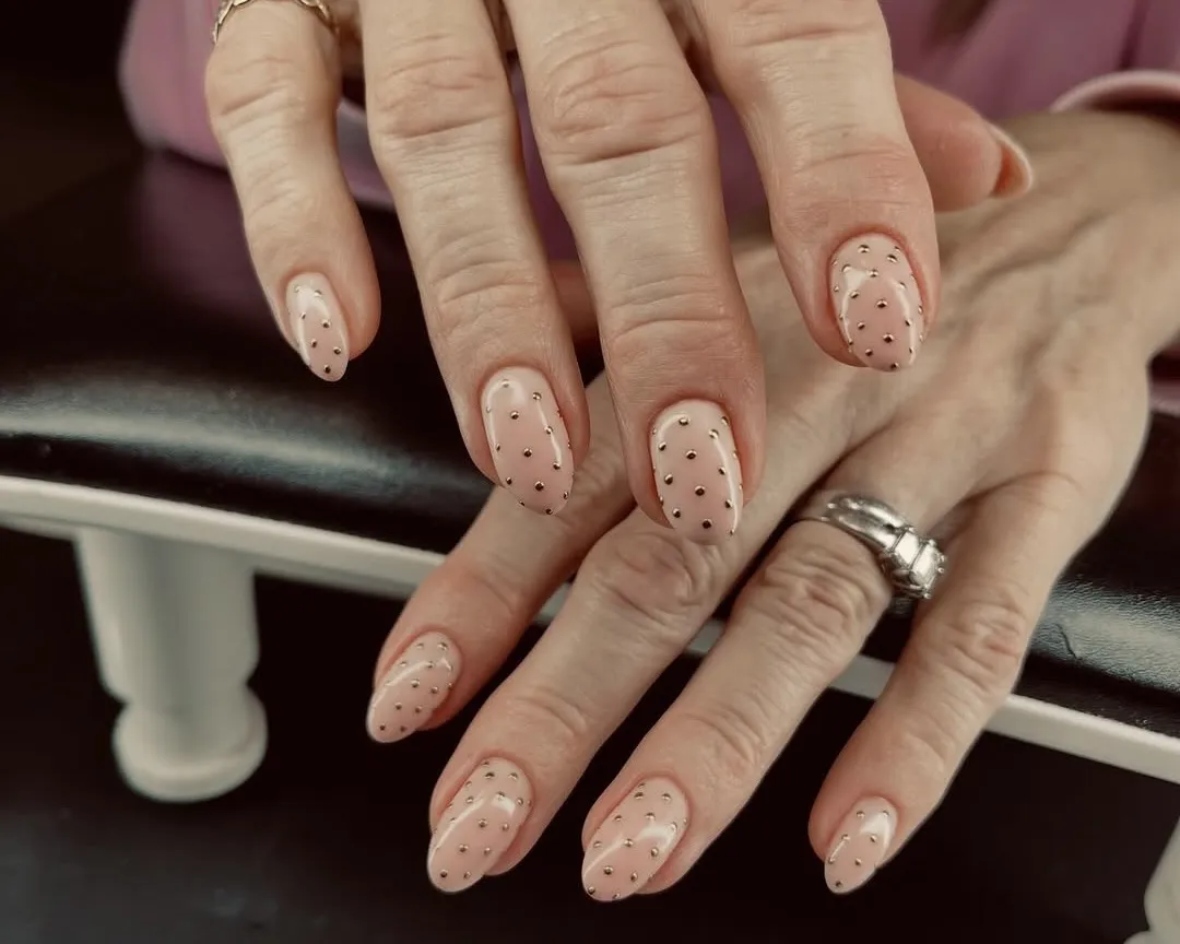 Gold chrome polka-dot nail art on a sheer base.