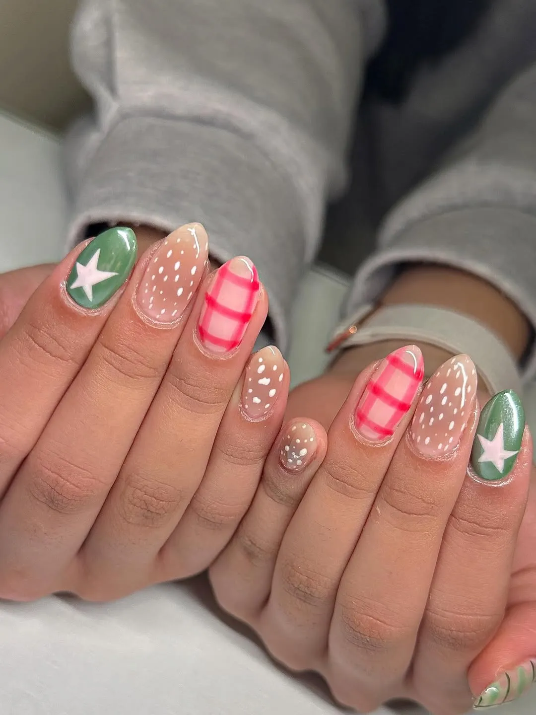 Hands displaying painted fingernails with decorative designs including stars and patterns