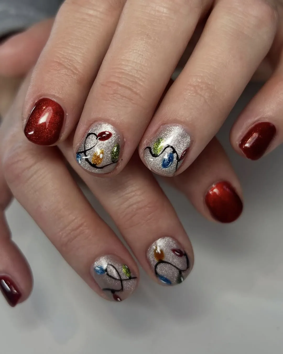 Red and silver Christmas nails with Christmas light nail art.