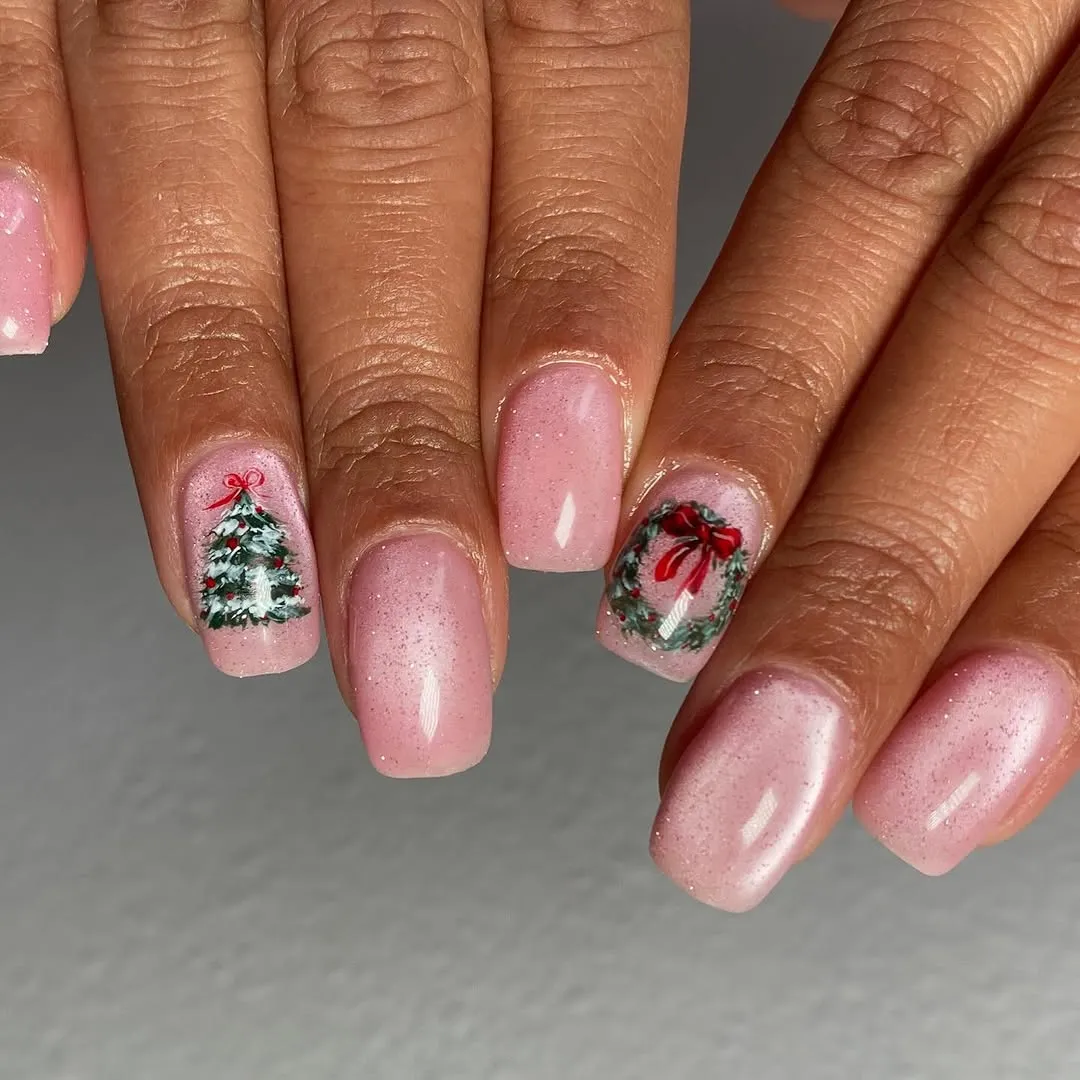 Hands with festive nail art including a Christmas tree and wreath design on the nails