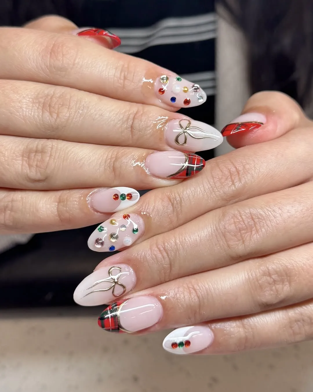 Red plaid French tip Christmas nails with rhinestone and bow accents.