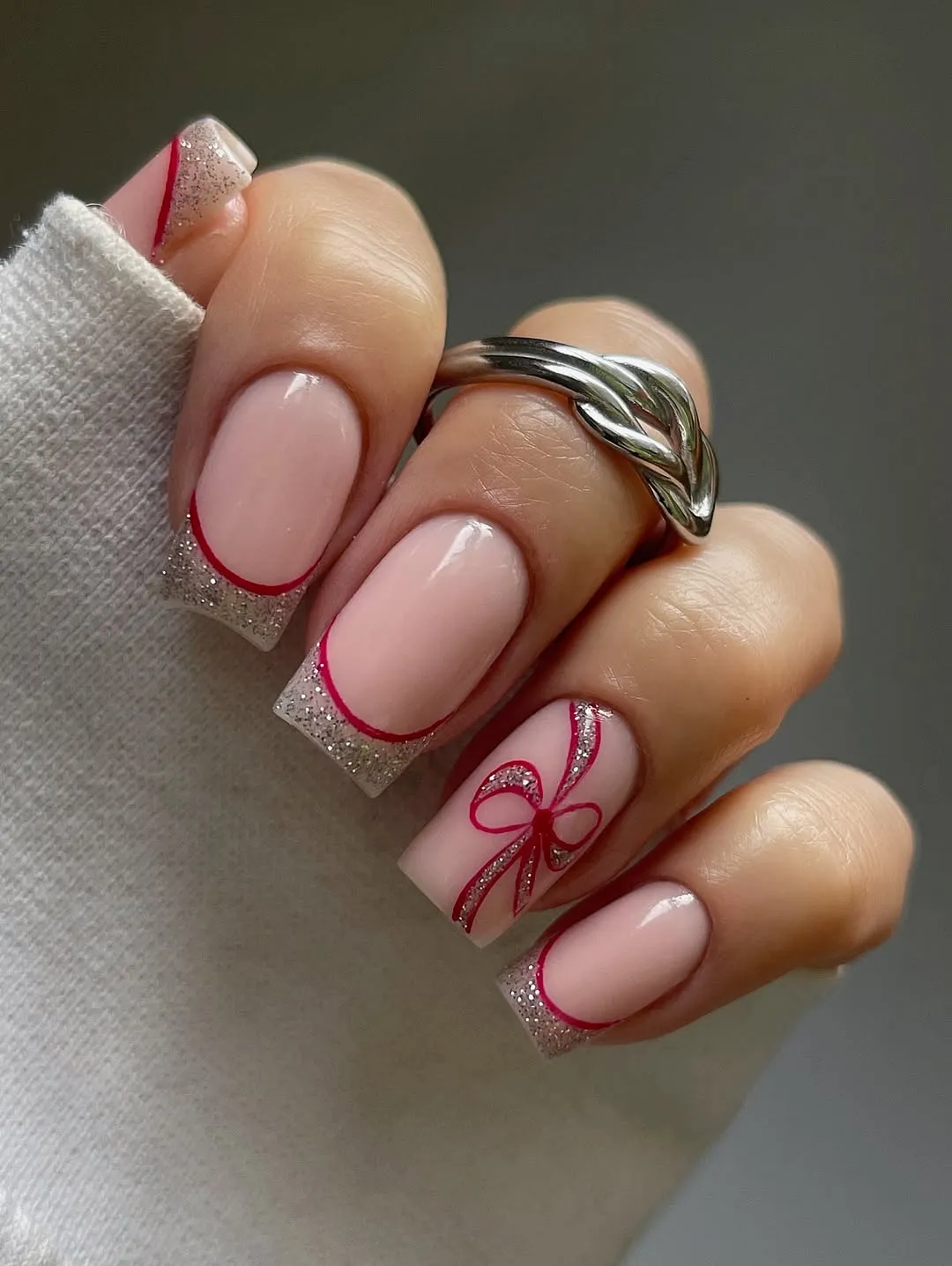 Nude nails with gold glitter and magenta French tip and ribbon designs