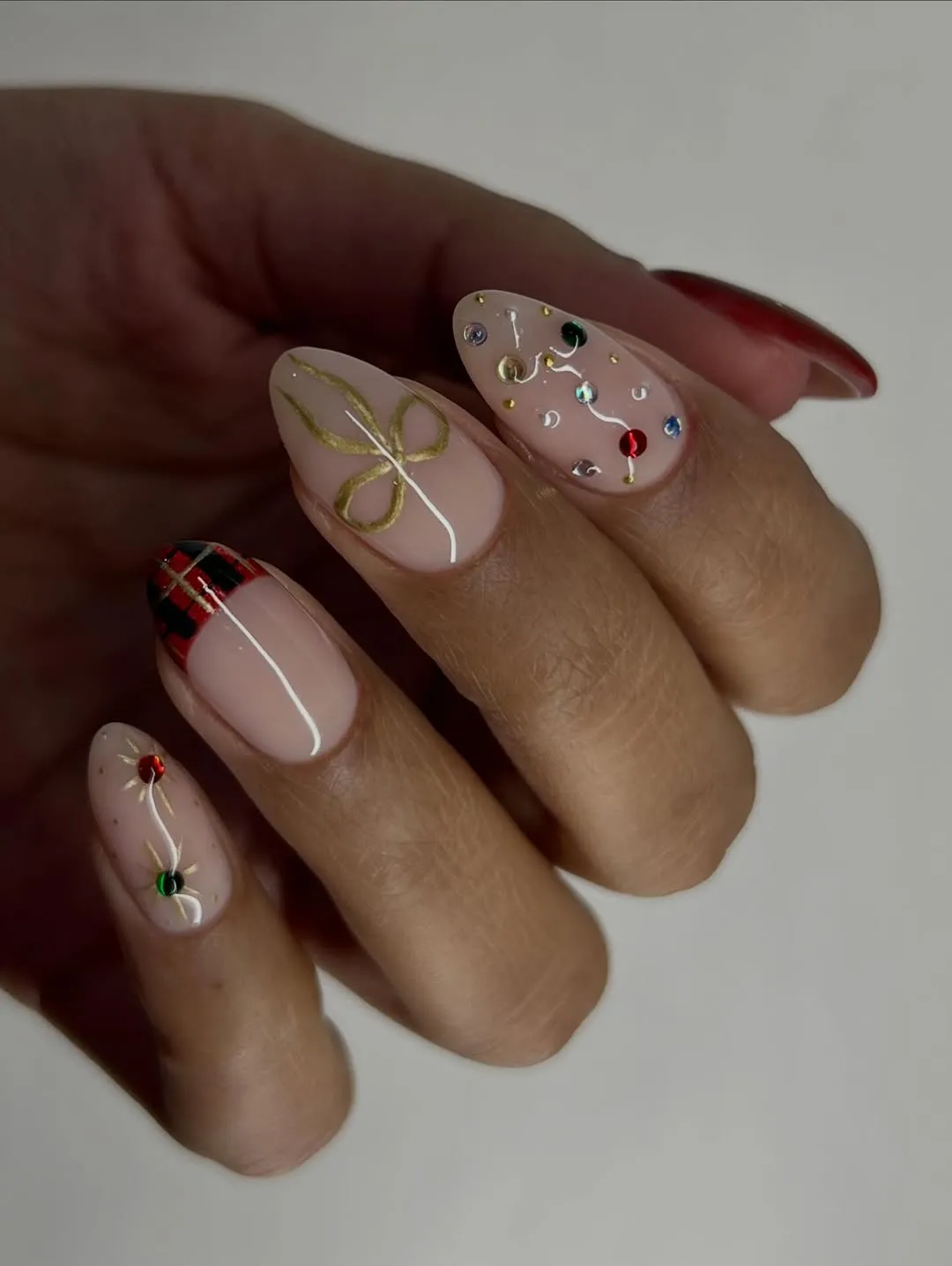 Pale pink manicure with plaid french tip, gems, and a bow accent