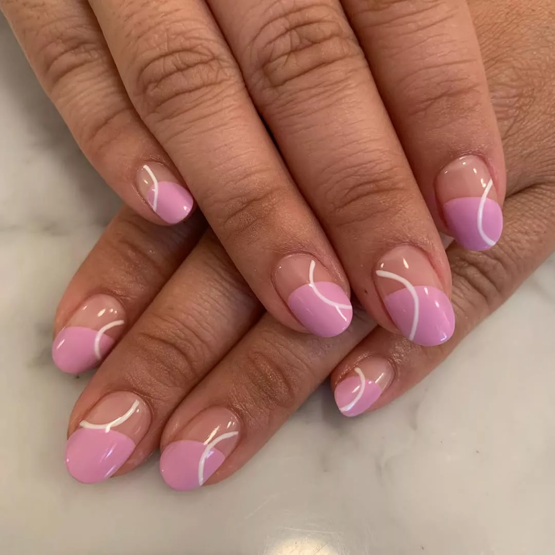 Person showing off their short, rounded nails, which have a pink French tip and white arch