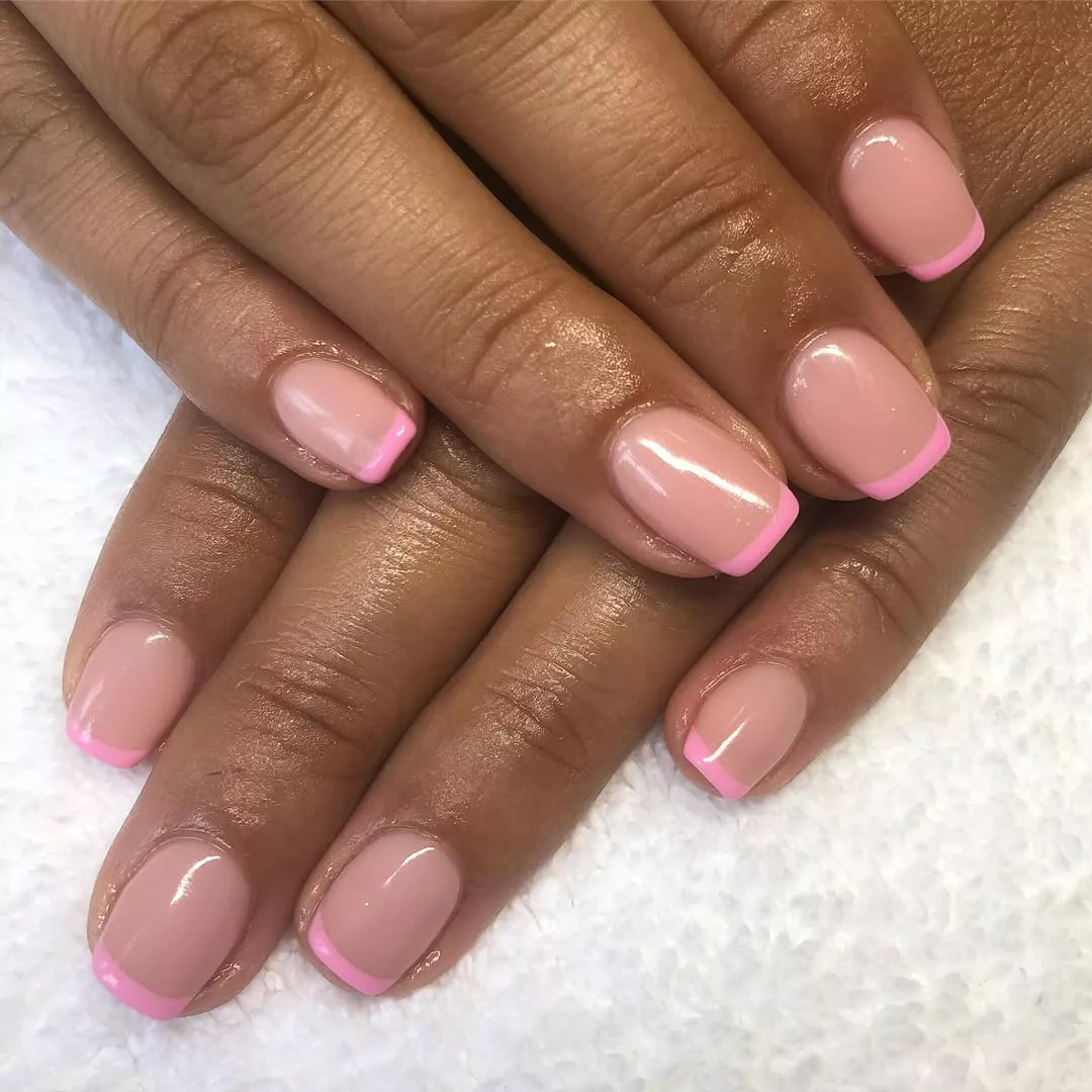 Person with pink French tip nails, which have a thin line at the top and mauve at the base