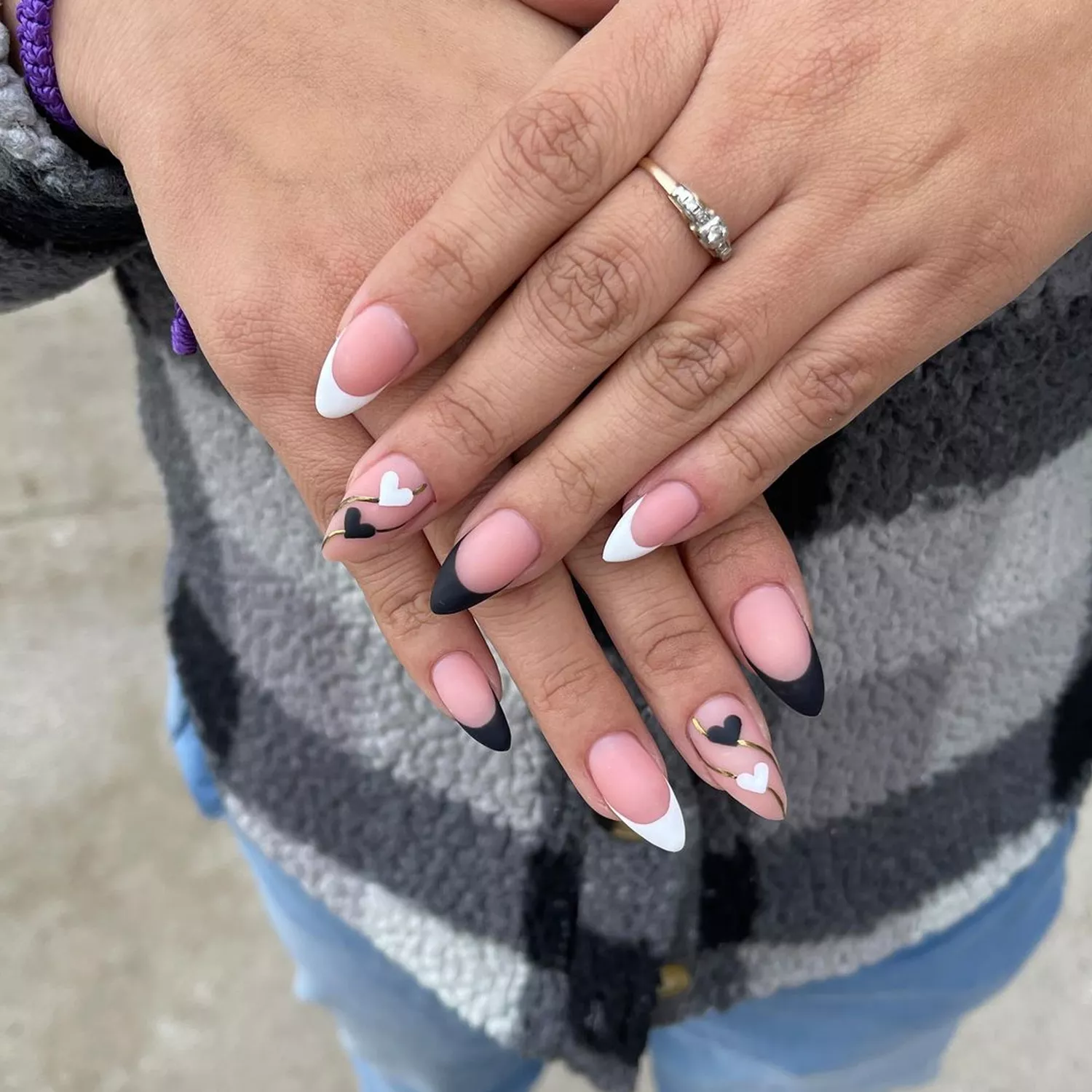 Almond-shaped nails painted with a black and white matte heart French manicure
