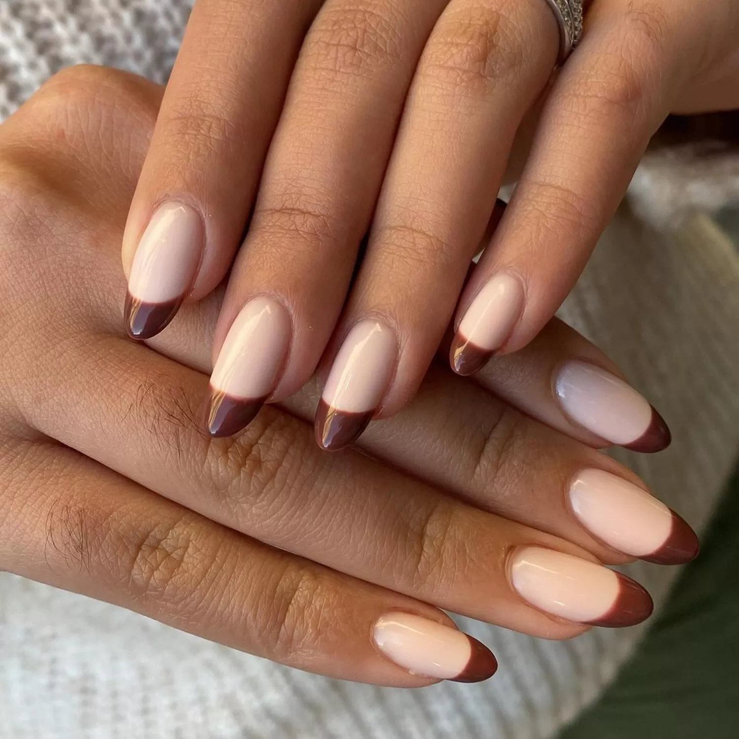 Glossy brown French manicure on almond-shaped nails
