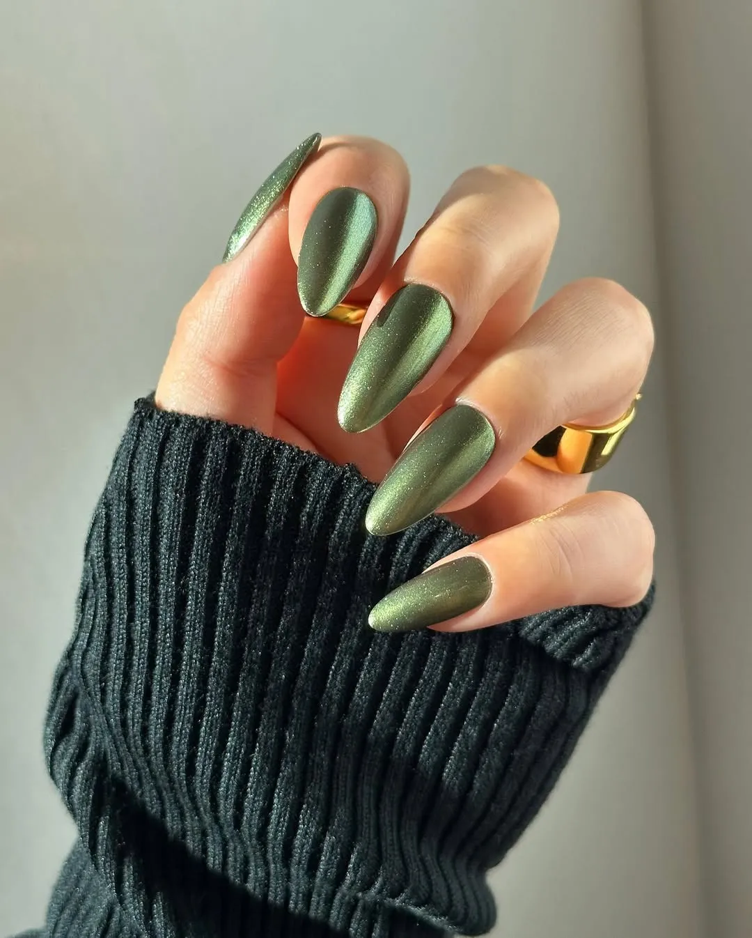 Medium-length almond-shaped nails in a metallic green polish