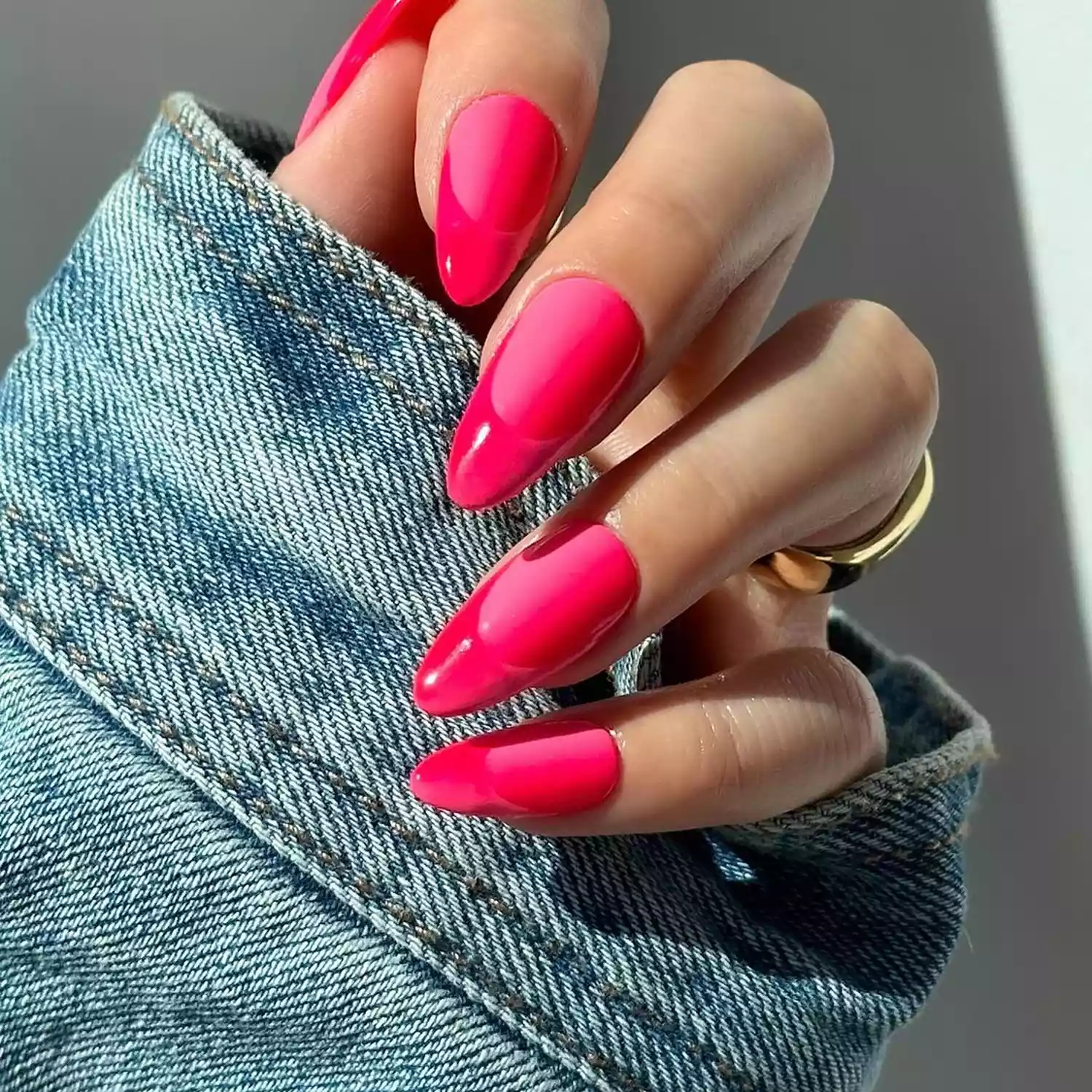Dual-finish hot pink French manicure against a blue denim jacket
