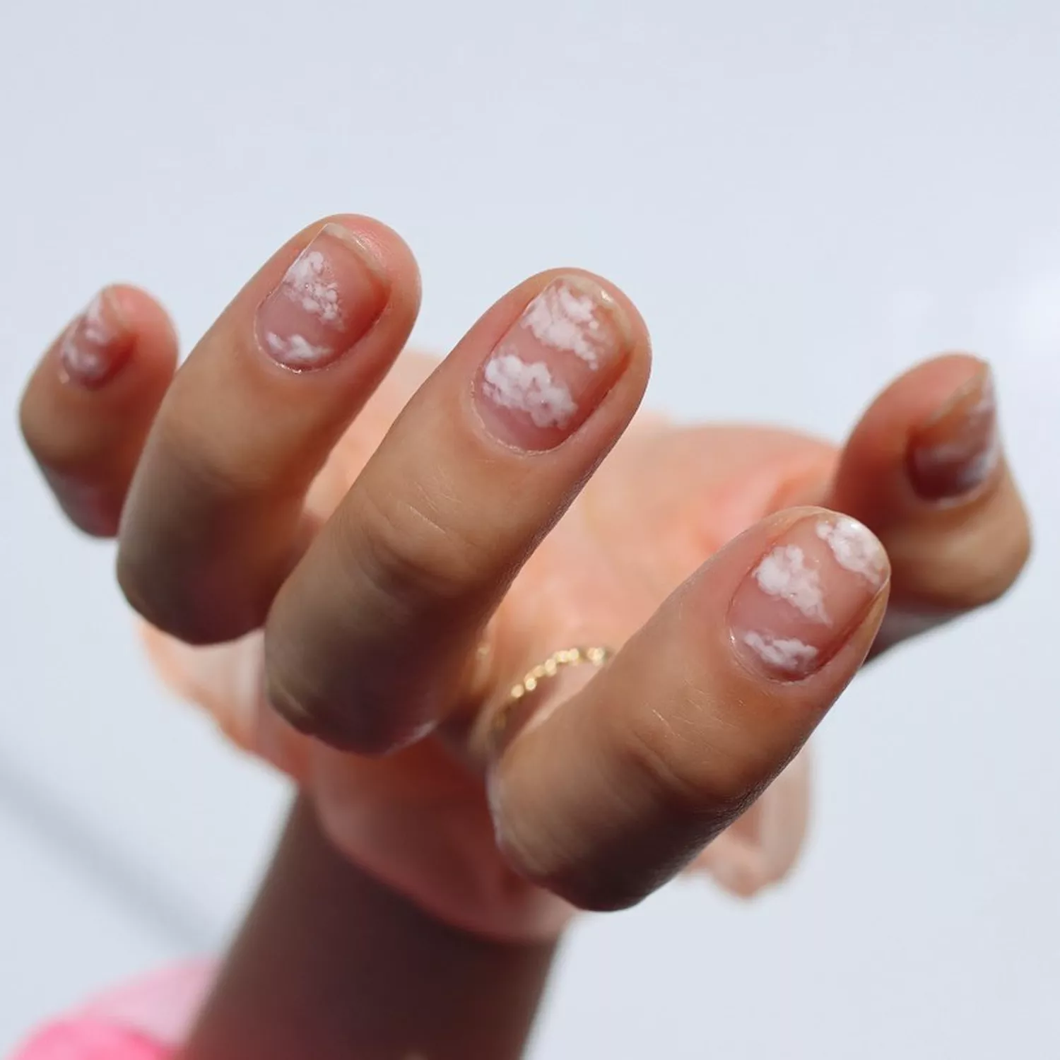 Person holds their hand upside down to show off their cloud-inspired manicure