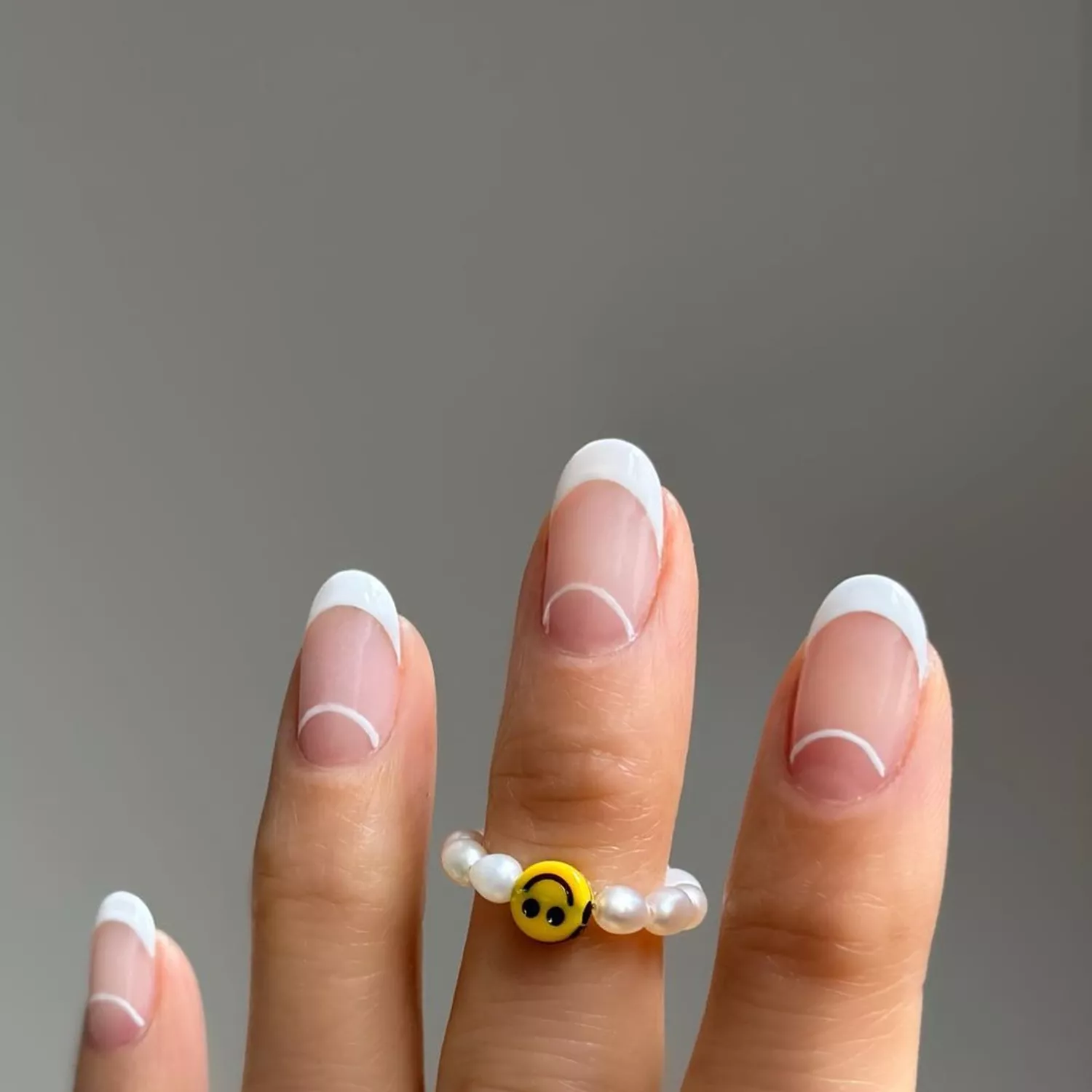 Person shows off their French manicure, which has negative space half moons at the base