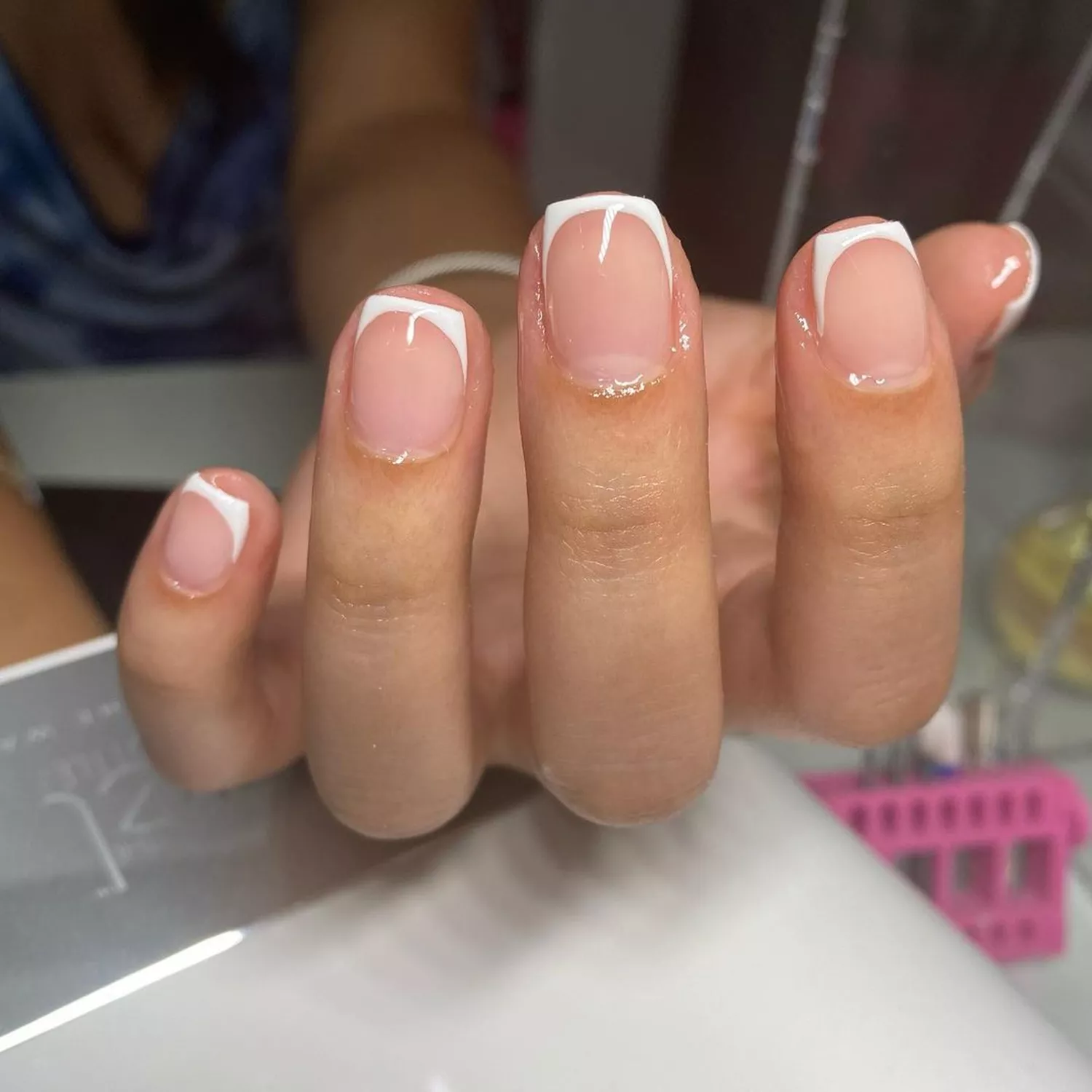 Person showing off their short French tip manicure, which is a simple white nail design