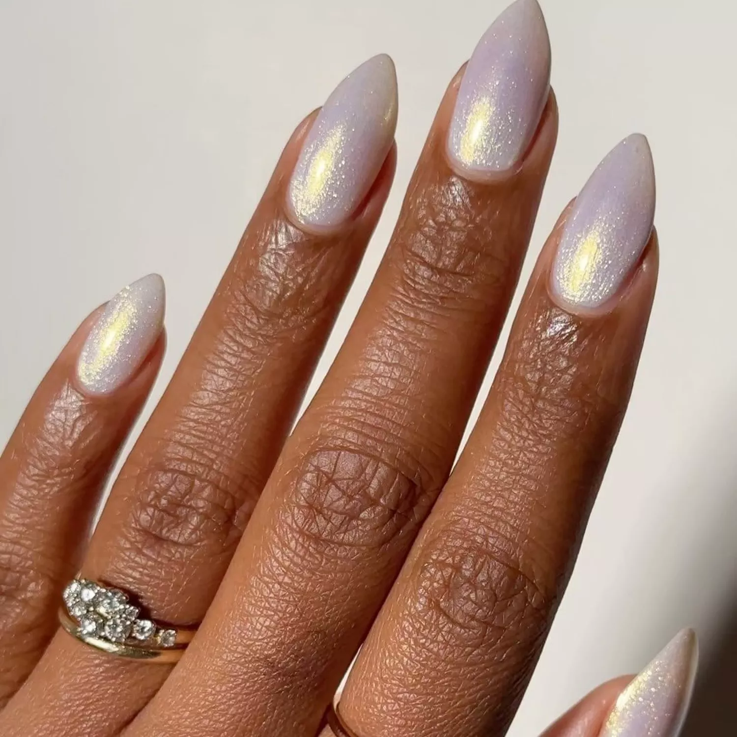 Person shows off their almond-shaped nails which are and iridescent, frosty white