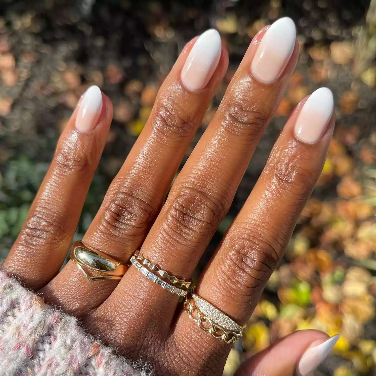 Person showing off their simple white nails, which are a light peach at the bottom