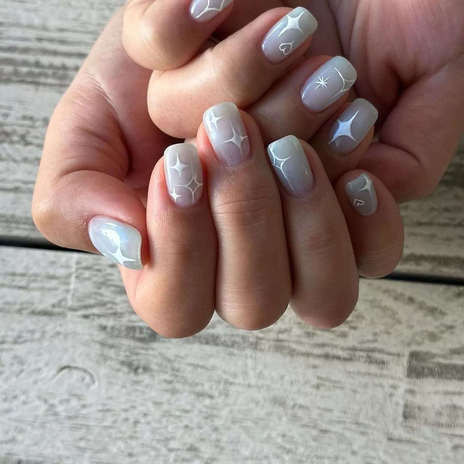 Person shows off their milky white nails, which have white sparkle accents on each nail
