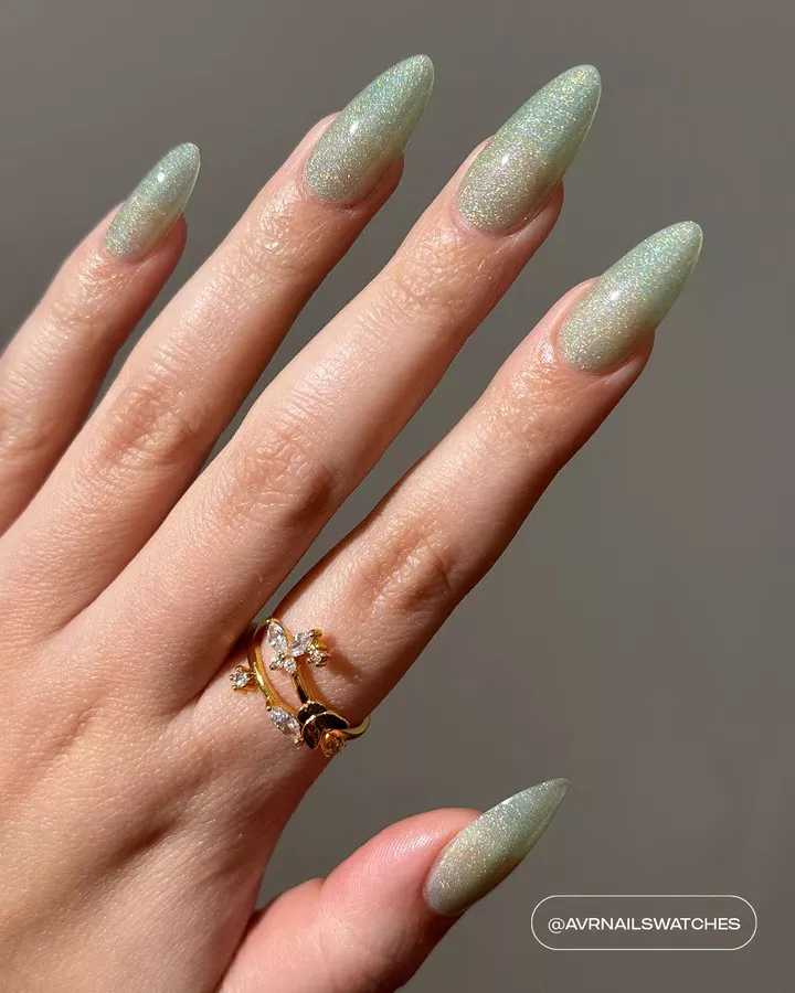 Person shows off their long, almond-shaped nails, which are painted in a glittery, mint green polish