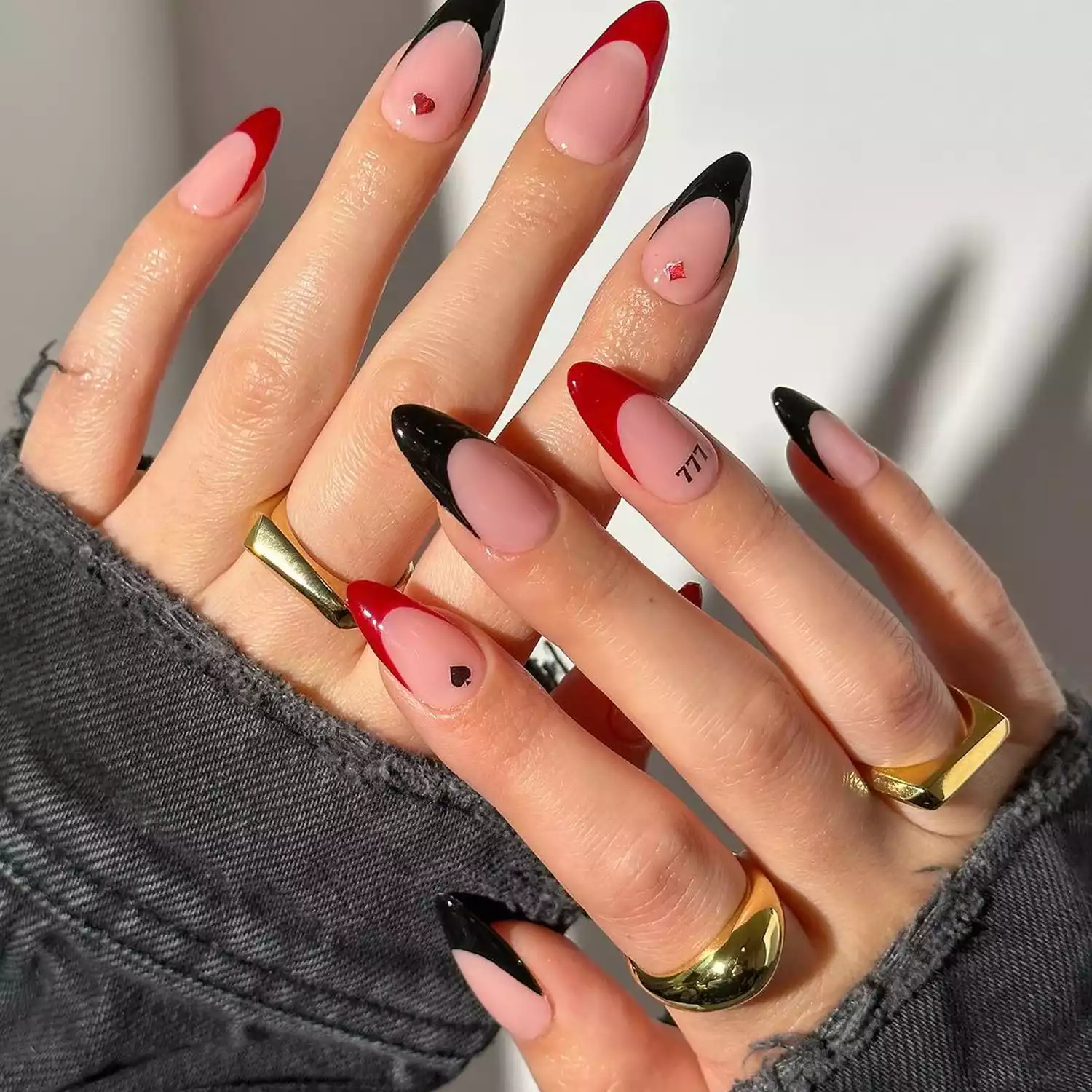 Red and black French tips on almond-shaped nails with card symbol cuticle accents