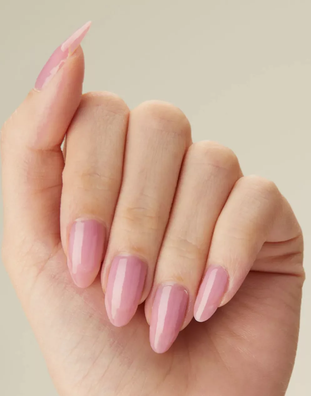 Person with almond-shaped nails painted in a sheer dusty rose polish