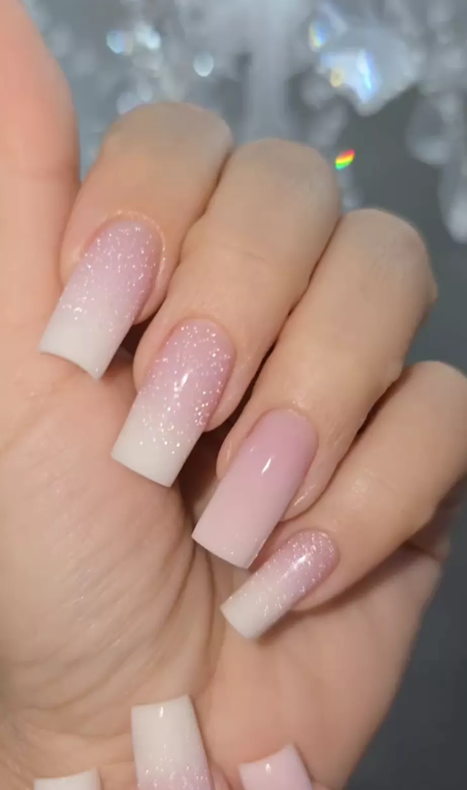 A white ombre nail design with silver glitter.