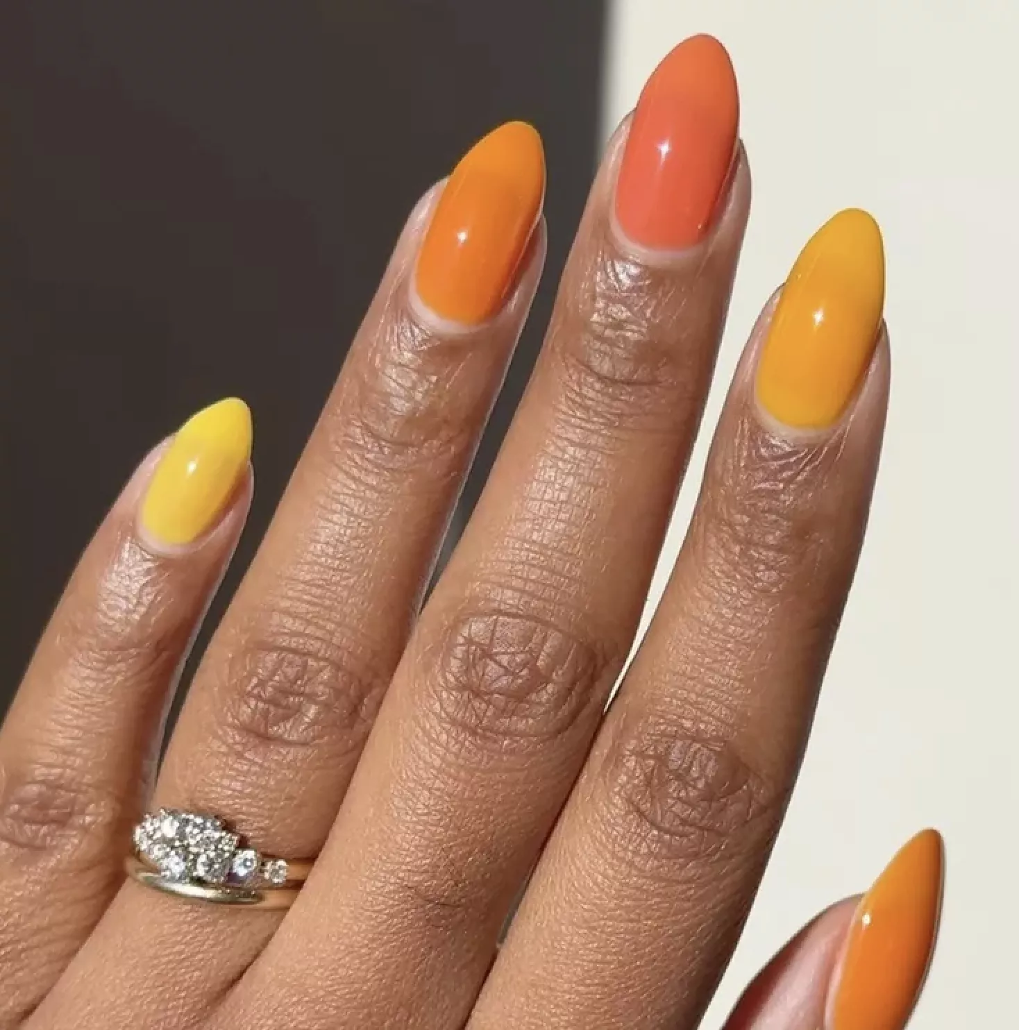 Person shows off their orange and yellow nails, painted in jelly polish