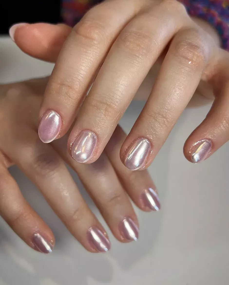 Person shows off their short, round-shaped, pearlescent nails