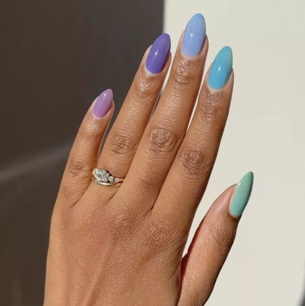 Person shows their sheer, jelly nails in purple, blue, and green polishes