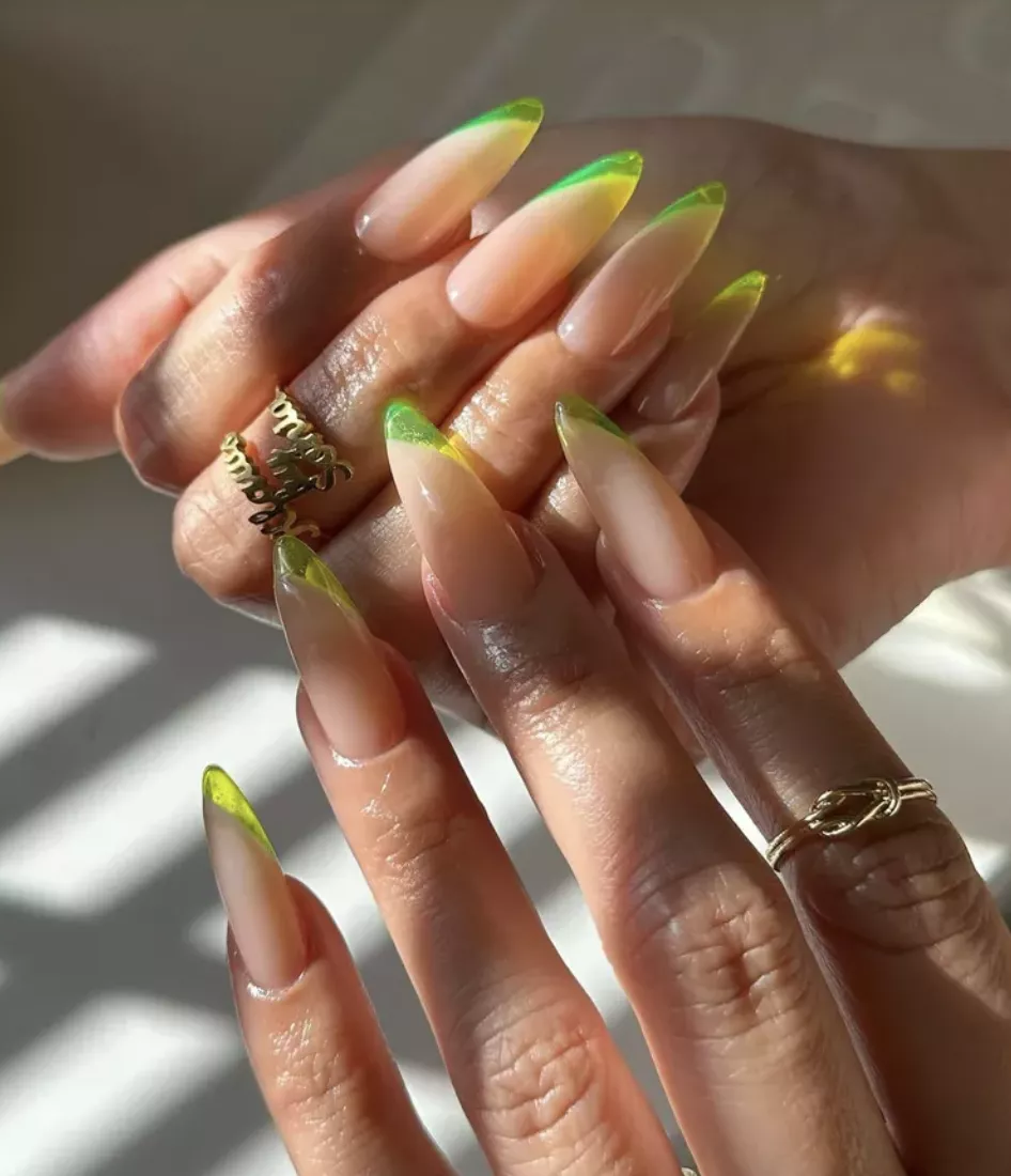 Person shows off their long, almond-shaped nails, which feature lime green jelly tips