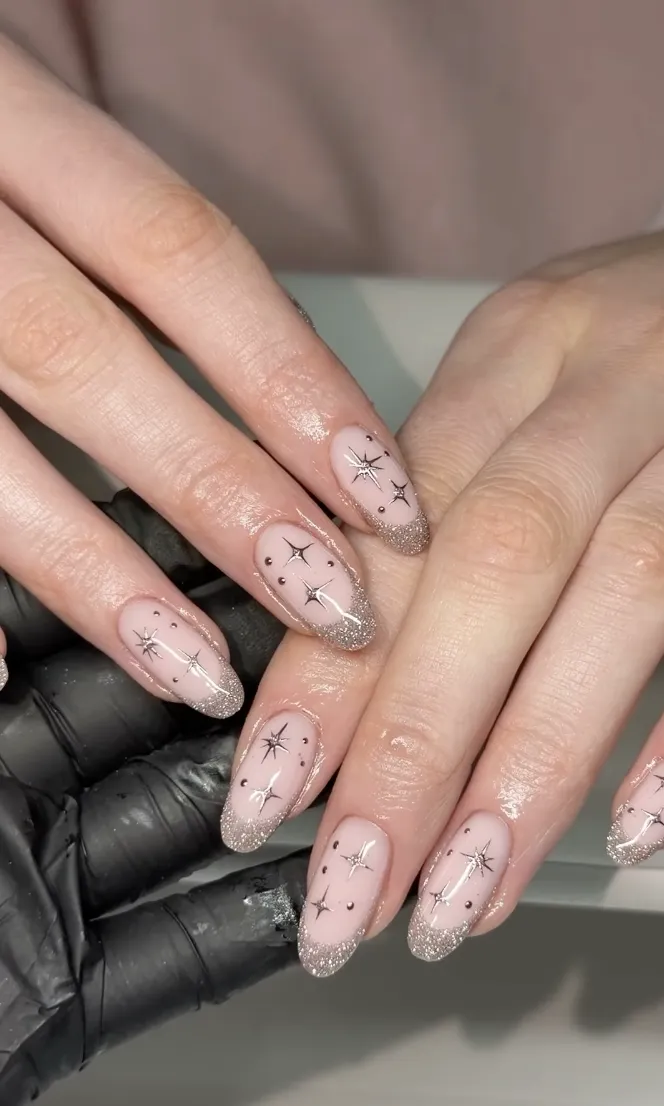 Hands with manicured nails featuring glitter and star designs held by another gloved hand