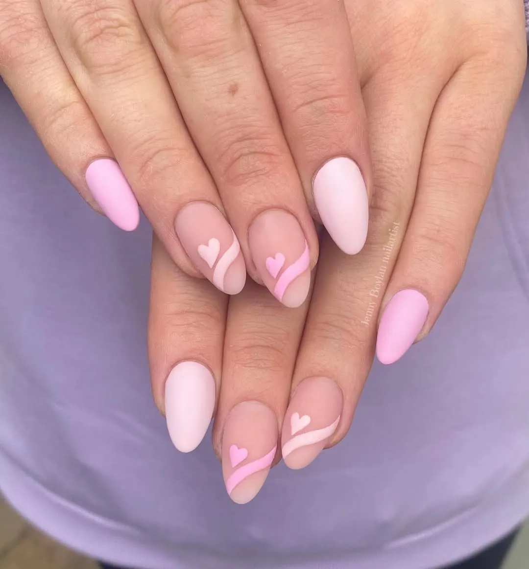 Matte light pink nails with nude accent nails, featuring hearts and swooshy lines