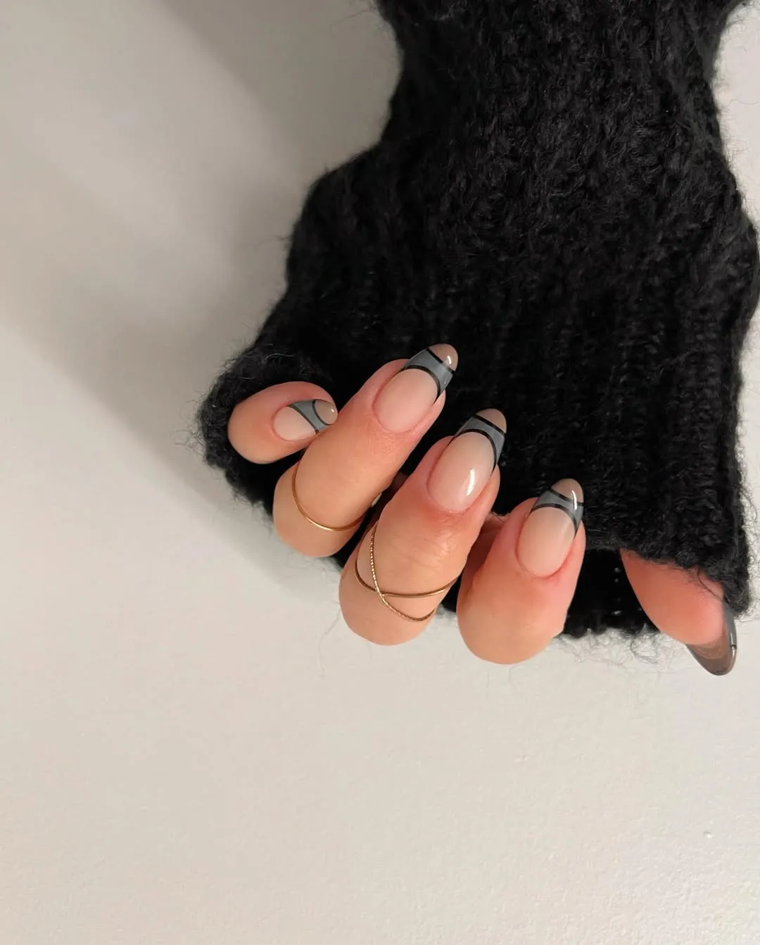 A french manicure with grey, black and brown designs at the tips