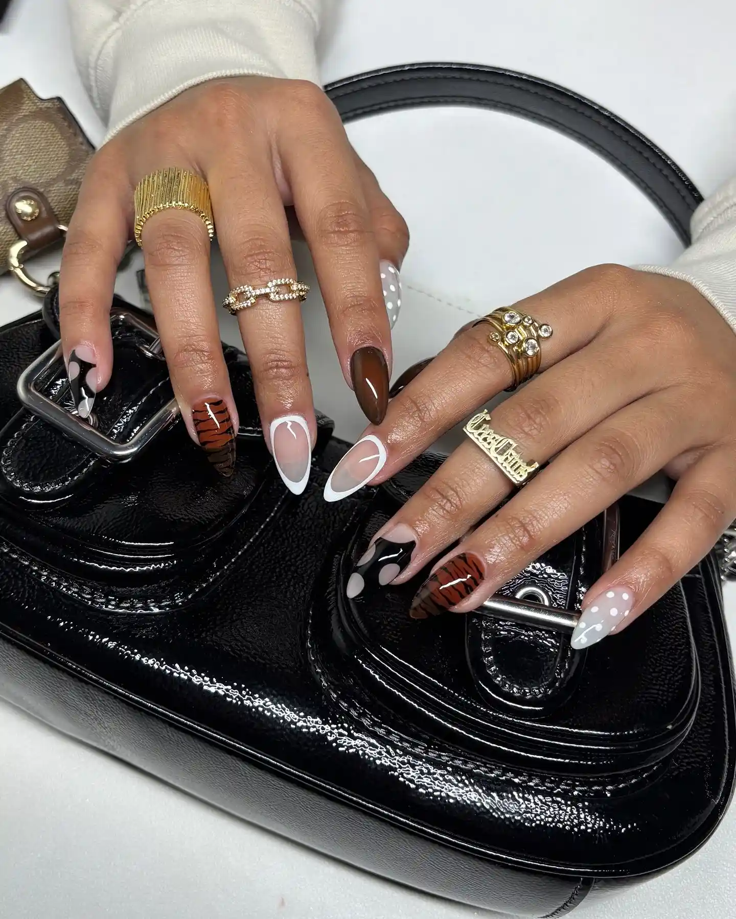 Person shows off their long, almond-shaped nails featuring tiger print and polka dots