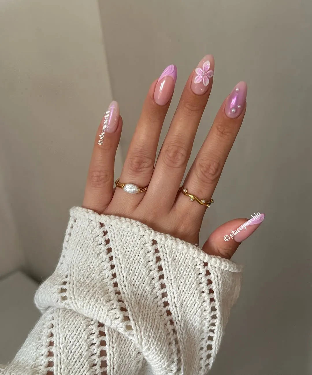 Nails with light pink french, aura designs and a flower design on the middle finger