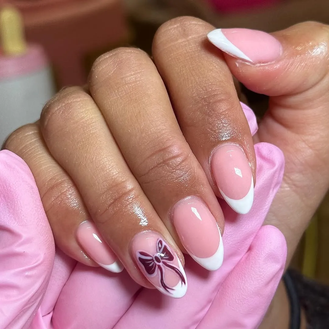 French tips with a single maroon bow on the ring finger