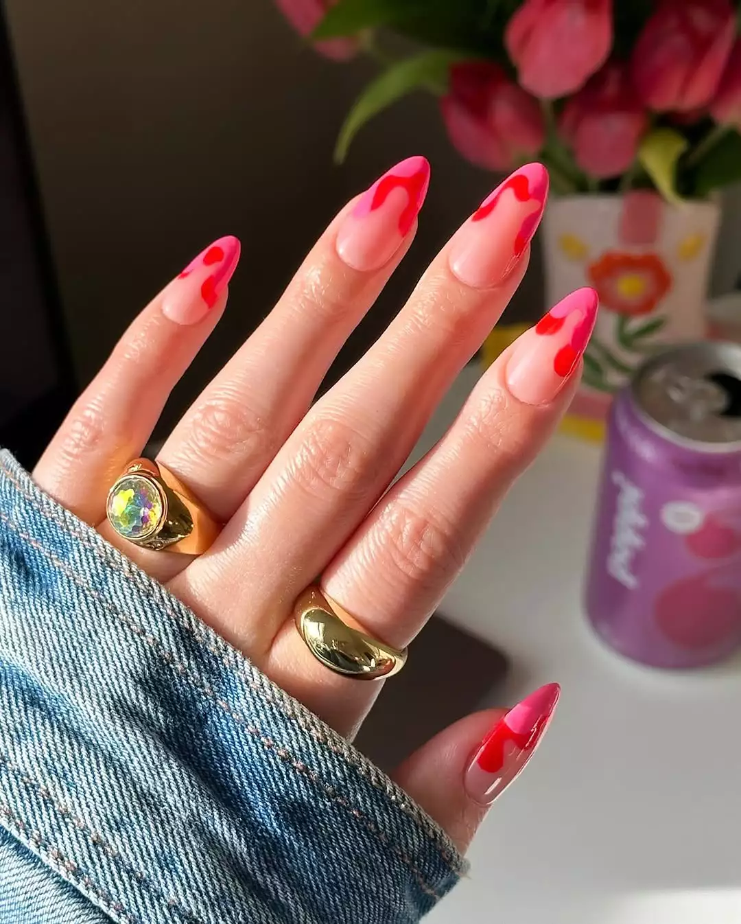 Person showing off their red and pink French tip nails, which are medium-length and almond-shaped