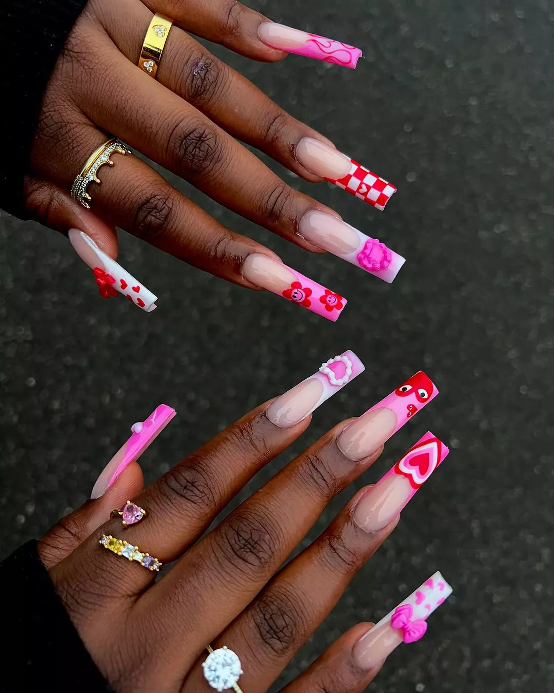 Person with extra long, square-shaped nails featuring pink French tips and hearts