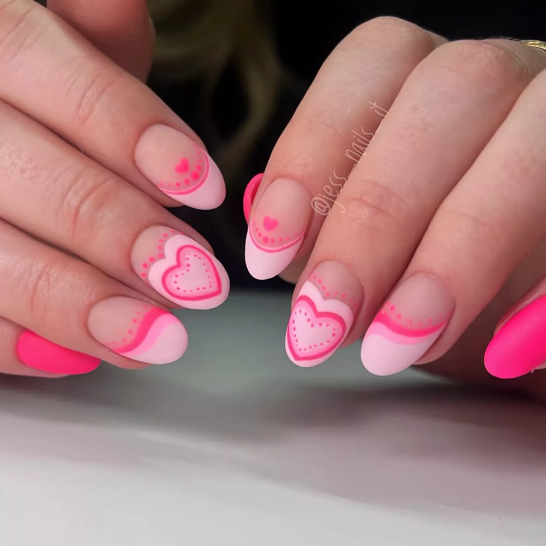 Person shows off their matte pink French tip nails, which feature hearts on each nail