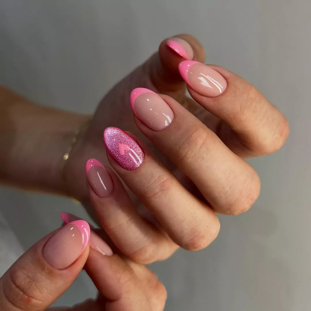 Person shows off their short, almond-shaped nails with pink French tips and a cat eye accent nail